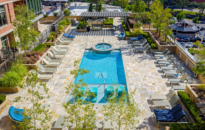 A large outdoor swimming pool surrounded by lounge chairs and greenery.