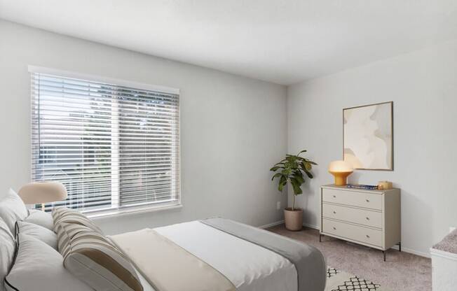 Model bedroom with a large window and a white dresser