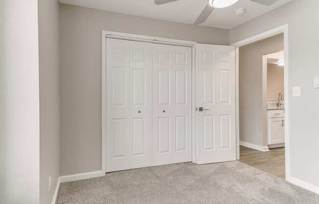 an empty bedroom with two closets and a ceiling fan