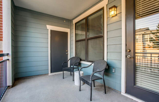 the front porch of a house with two chairs and a door