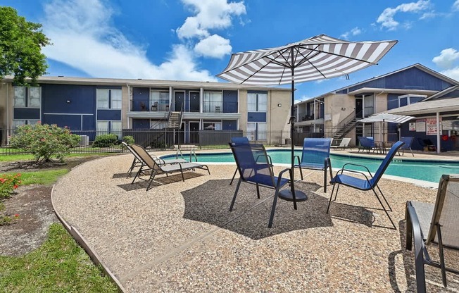 A sunny day at the poolside with chairs and an umbrella.