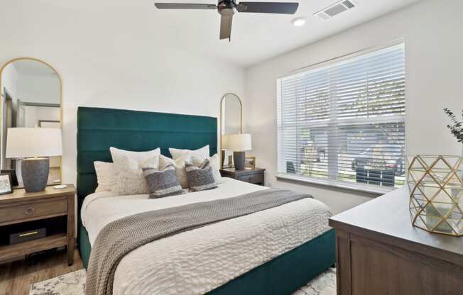 a bedroom with a large bed and a ceiling fan at The Depot in The Depot Raymore, MO 64083