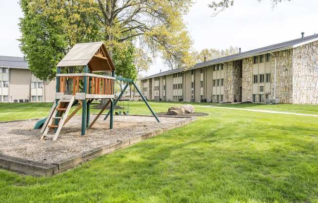 a swing set in the middle of a grassy area with a stone building in the background