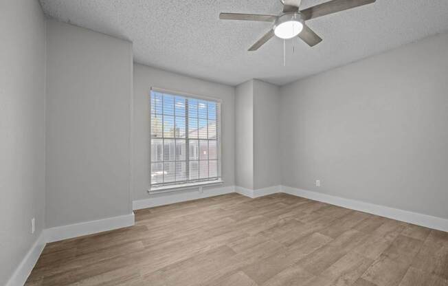 Empty room with a ceiling fan and a window.