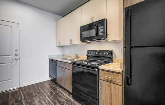 Apartments for Rent Phoenix, AZ - Large Kitchen with Black Appliances, Wood Flooring, and Brown Cabinetry