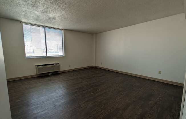 an empty living room with wood floors and a window