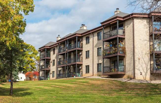 an apartment building on a hill with a green lawn