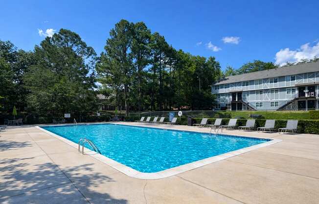 A large swimming pool surrounded by trees and lounge chairs.