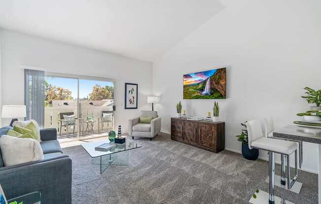 a living room with white walls and a sliding glass door to a balcony