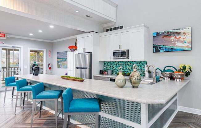 A kitchen with a white island and blue chairs.