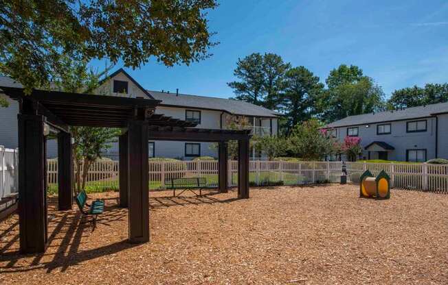 A gravel area with a wooden structure and a fence in the background.