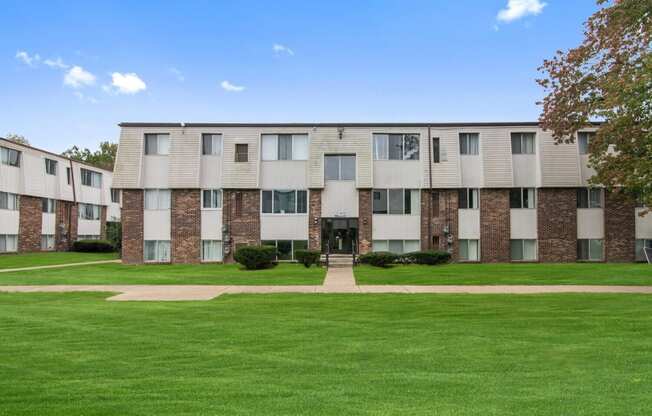 an exterior view of an apartment building with green grass