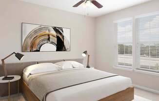 A bedroom with a large bed, a ceiling fan, and a painting on the wall.