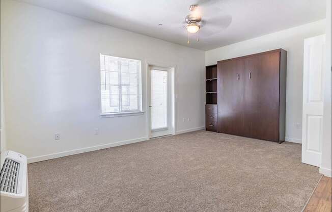 A room with a brown wardrobe and a window with blinds at Riverplace Apartment Homes, Independence, OR, 97351