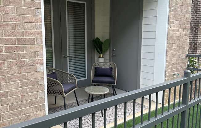 a porch with two chairs and a table on a balcony