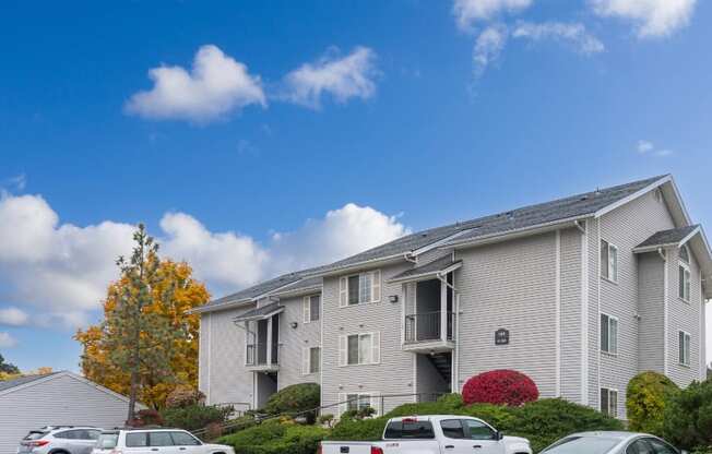 the view of an apartment building with cars parked in front of it