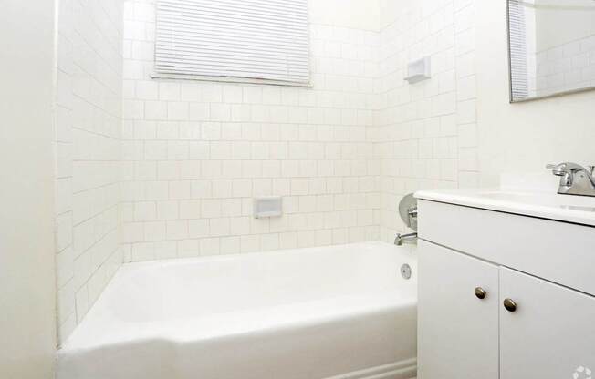 A white bathroom with a tub, sink, and mirror.