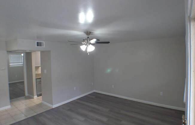 an empty living room with a ceiling fan