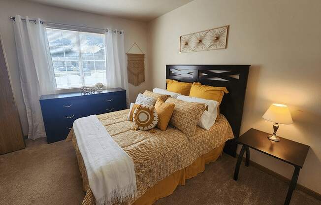 A bedroom with a bed, nightstand, and window.
