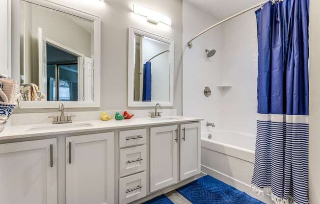 a bathroom with white cabinets and a shower and a sink and a mirror