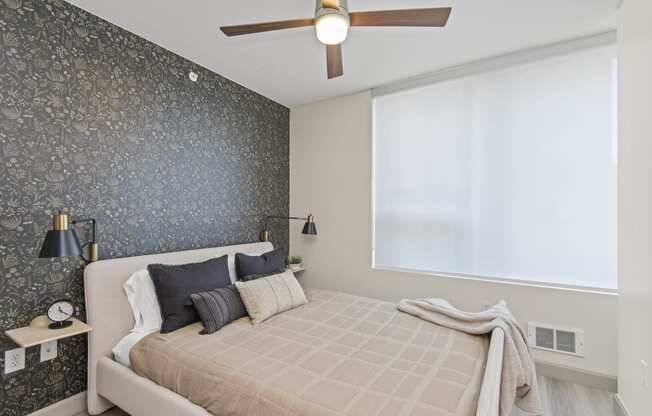 a bedroom with a dark accent wall and a ceiling fan