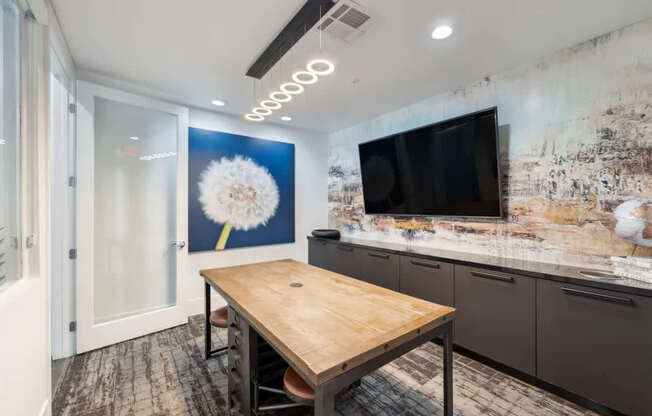 A room with a wooden table and a TV on the wall.