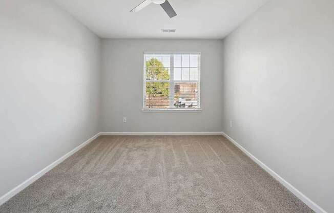 A room with a window and a fan on the ceiling.