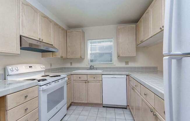 A kitchen with white appliances and wooden cabinets.