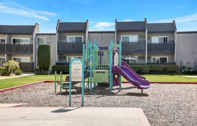 A playground with a purple slide and a green and white sign.