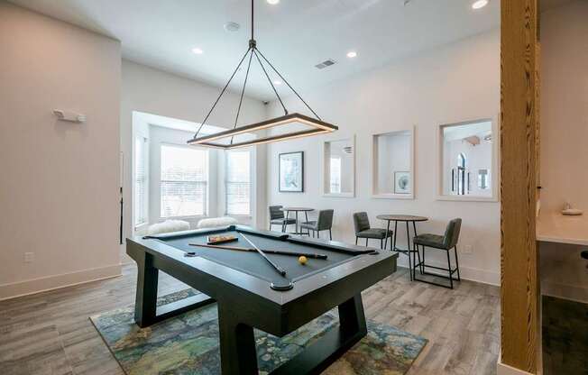 A pool table is in the middle of a room with a light hanging from the ceiling.
