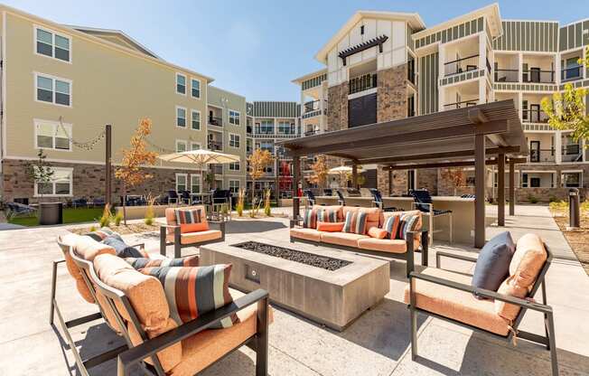 A patio with a fire pit and chairs.