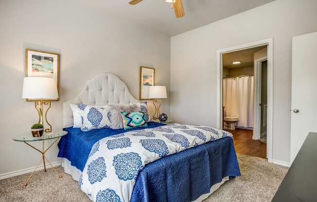 A bedroom with a bed covered in a blue and white patterned bedspread.