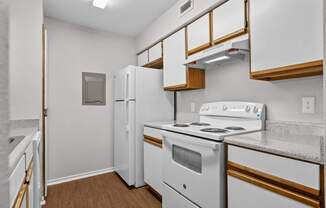 A kitchen with white appliances and wooden cabinets.