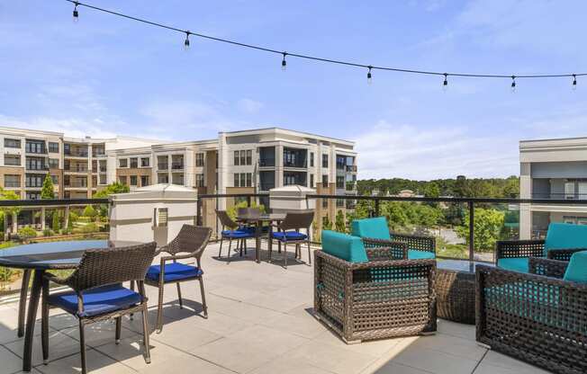 a rooftop patio with tables and chairs and a building in the background