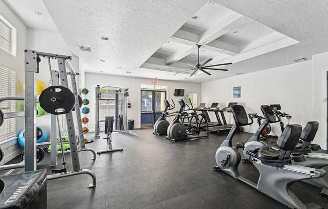 A gym with a variety of exercise equipment including treadmills, stationary bikes, and weight machines.