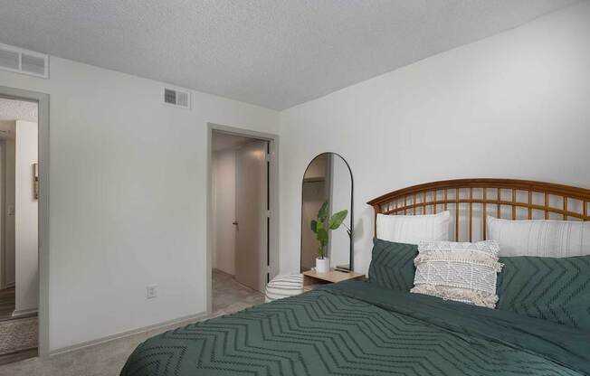 A bedroom with a bed and a mirror on the wall.