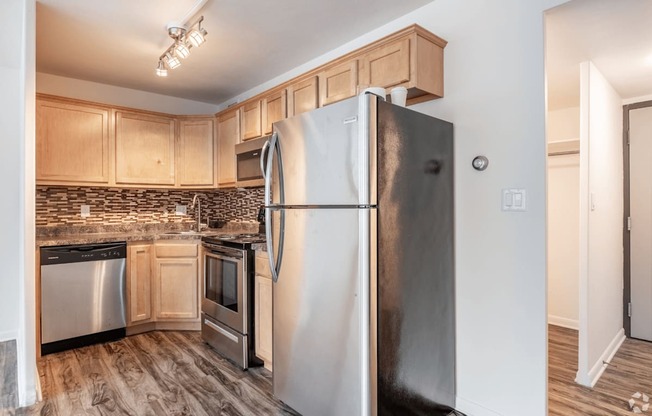 A kitchen with a stainless steel refrigerator and wooden cabinets.