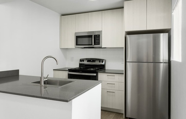 A modern kitchen with a stainless steel refrigerator, microwave, oven, and sink.
