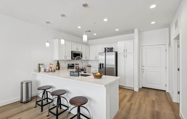 A kitchen with white cabinets and a white island with a counter top.