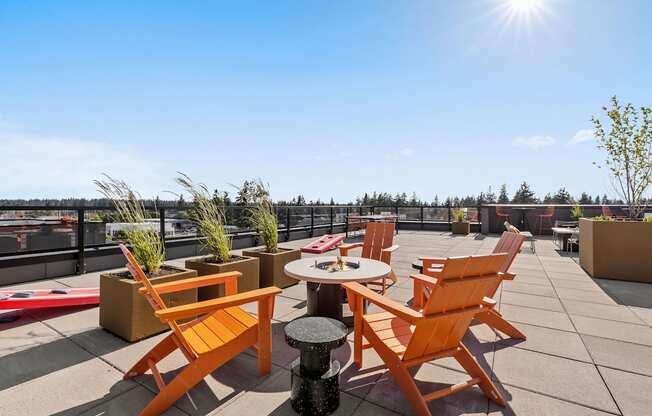 a rooftop terrace with orange chairs and a table with a pizza box on it at Ion Town Center, Shoreline, 98133