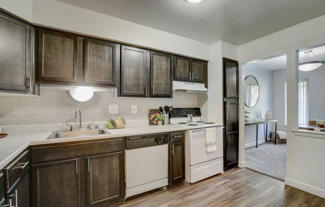 a kitchen with white appliances and dark wood cabinets - Maple Place Apartments