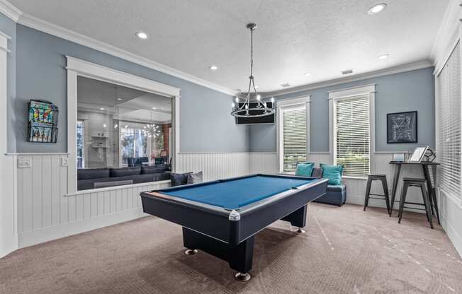 a game room with a pool table with pendant lighting  and a window at Eagles Landing Apartments, Ammon, 83406