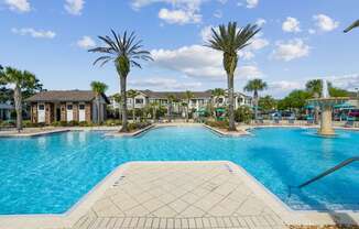 A large swimming pool surrounded by palm trees and residential buildings.