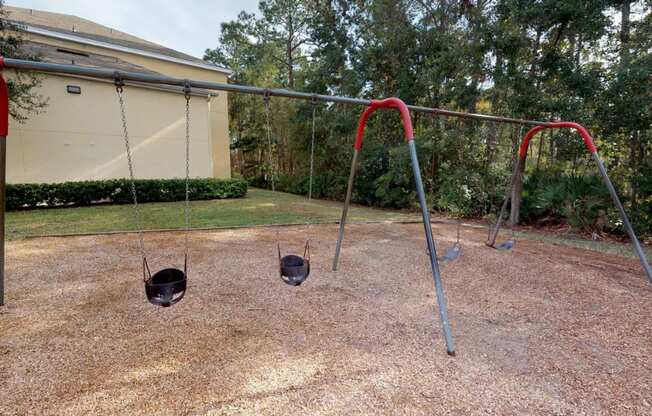 A playground with two swings and a red canopy.