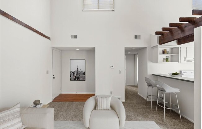 a living area with a white couch and a chair and a bar with stools