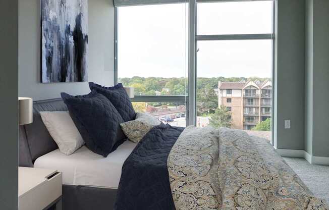 A bedroom with a bed, a couch, and a painting on the wall.