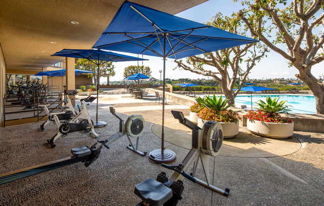 a workout area with weights and umbrellas near a swimming pool