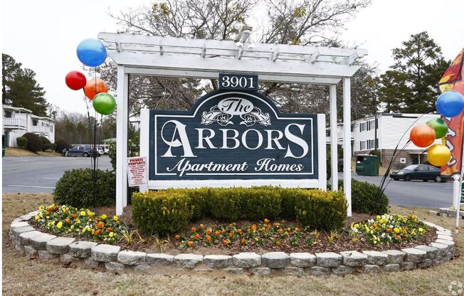 the arbors sign in front of a yard with balloons