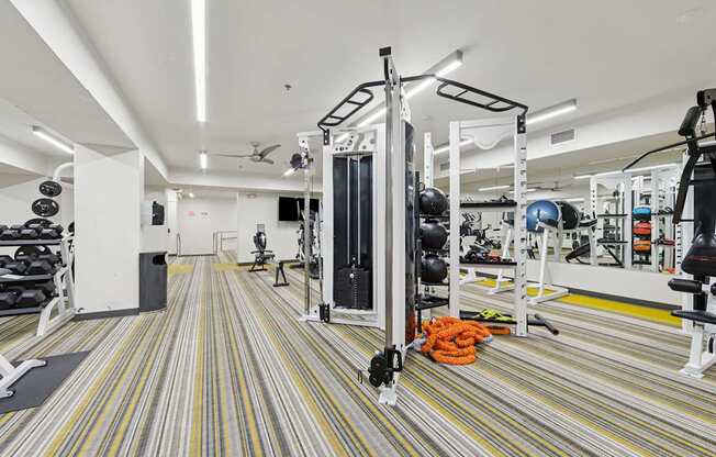 A gym with a striped carpet and a variety of equipment.