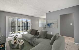 A living room with a grey couch and a painting on the wall.